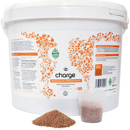 A white bucket labeled 'charge' with a orange and green design, next to a clear cup containing a brown powder, with a small pile of the same brown powder displayed in front.